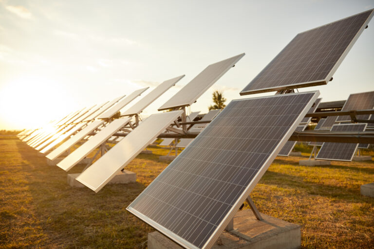 Photovoltaic panels installed in field against sundown sky on solar power station